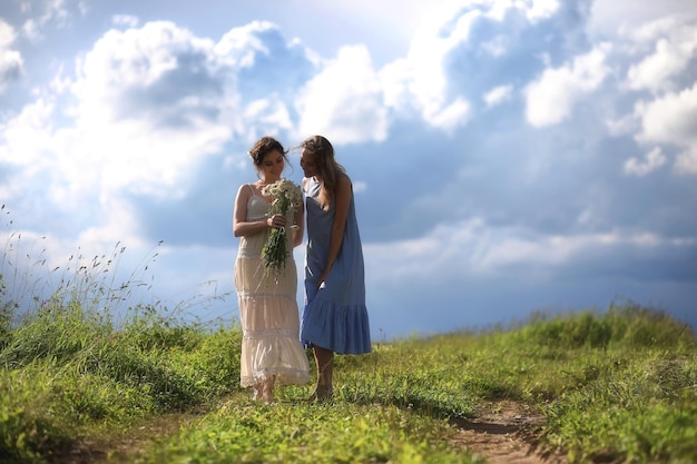 Young girls are walking in the field before the rain