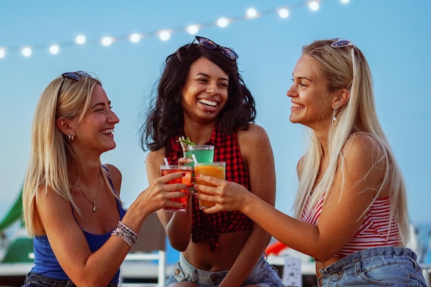 Young girls having a party in a beach Teenagers drinking cocktails Friends having fun in bar