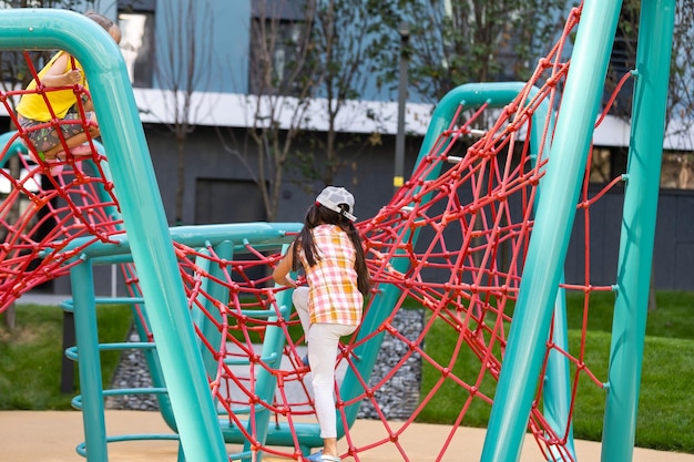 Young girls poking head through climbing rope activity using it as frame.