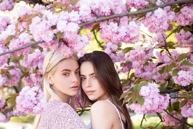 Giovani ragazze e fiori di primavera bella donna sensuale sexy in fiori rosa nel parco estivo in fiore