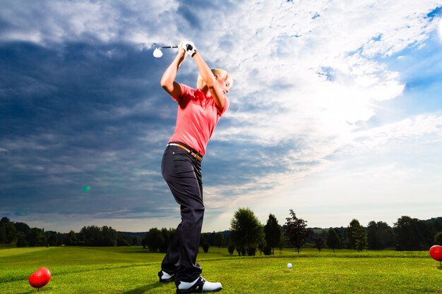 Young golf player on course doing golf swing