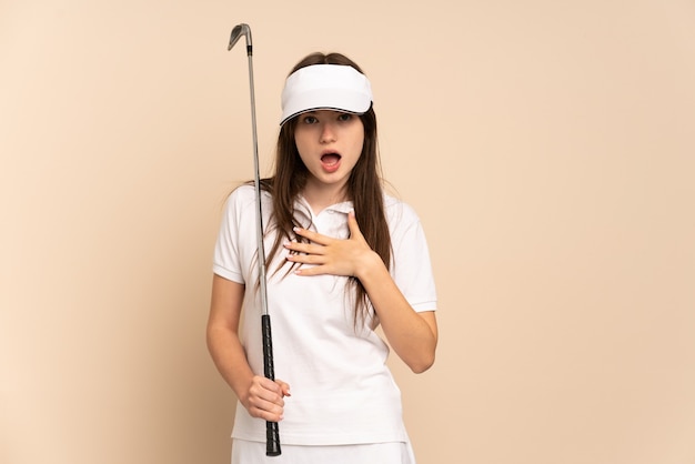 Photo young golfer girl isolated on beige surprised and shocked while looking right