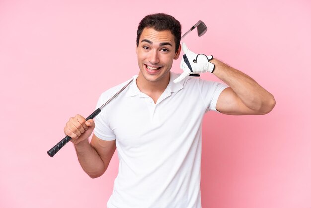 Photo young golfer player man isolated on pink background making phone gesture call me back sign