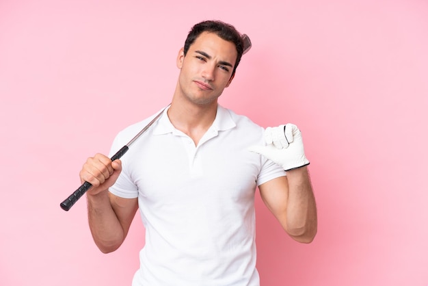 Young golfer player man isolated on pink background proud and selfsatisfied