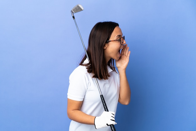 Молодая женщина-гольфист над красочной стеной, кричащая с широко открытым ртом в сторону