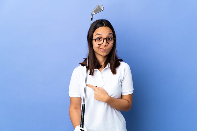 Young golfer woman over isolated colorful background pointing to the laterals having doubts