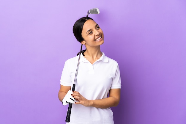 Young golfer woman over isolated colorful looking up while smiling