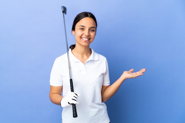 Young golfer woman over isolated colorful wall holding copyspace imaginary on the palm to insert an ad