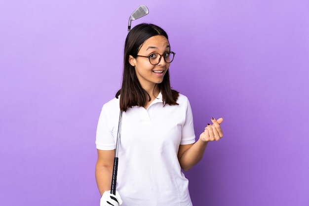 Young golfer woman isolated on purple