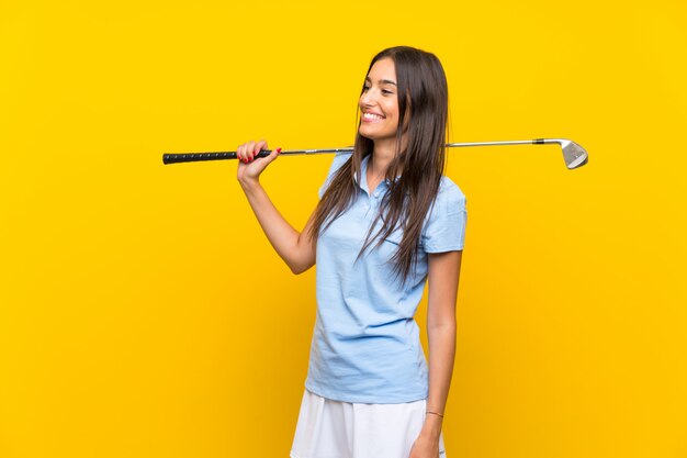 Young golfer woman  isolated on yellow wall