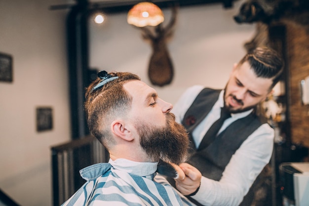 Giovane bell'uomo hipste visitando un barbiere. stile e taglio della barba alla moda ed eleganti.