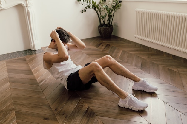 Young good looking man is working out on the floor of his house