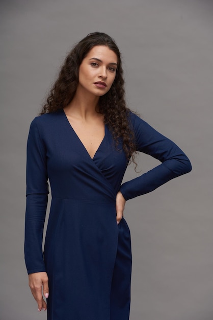 Young gorgeous woman in elegant smart casual blue dress looking at camera