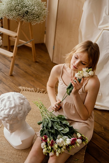 Foto giovane donna splendida in posa con statua e fiori primaverili
