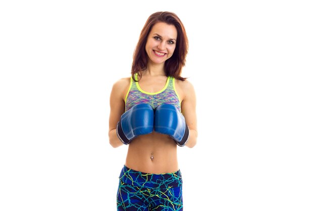 Young gorgeous woman wearing in colored sports top with boxing gloves on white background in studio