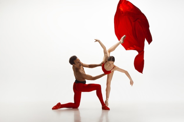 Young graceful couple of ballet dancers dancing on white studio background