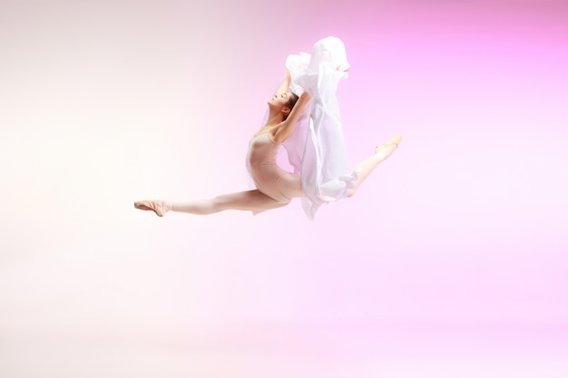 写真 ピンクのスタジオで踊る若い優雅な女性のバレエダンサーまたは古典的なバレリーナ。トウシューズの白人モデル