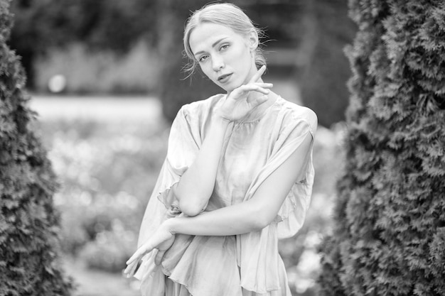 Young graceful female ballet dancer in theatrical dress posing in sunny park