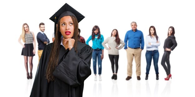 Young graduated black woman wearing braids thinking and looking up, confused about an idea