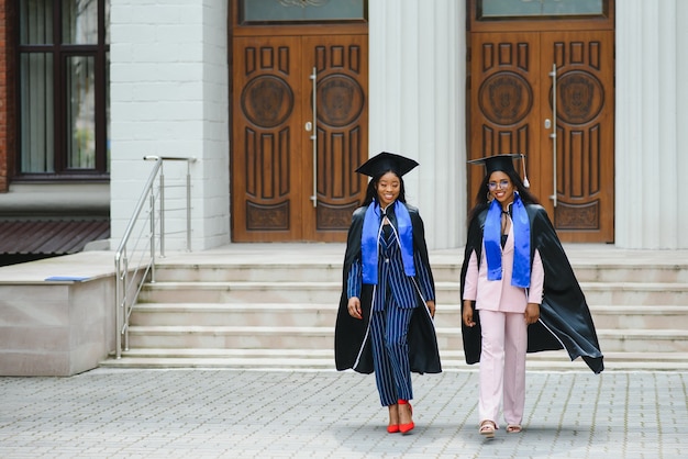 Giovani laureati in piedi davanti all'edificio universitario il giorno della laurea