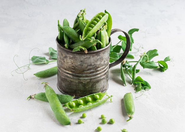 Young green peas pods in a metal cup