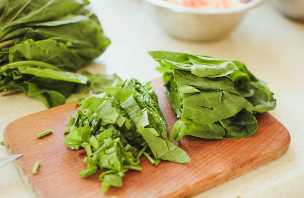 Young green sorrel sliced for borscht and salad lies on a cutting board.