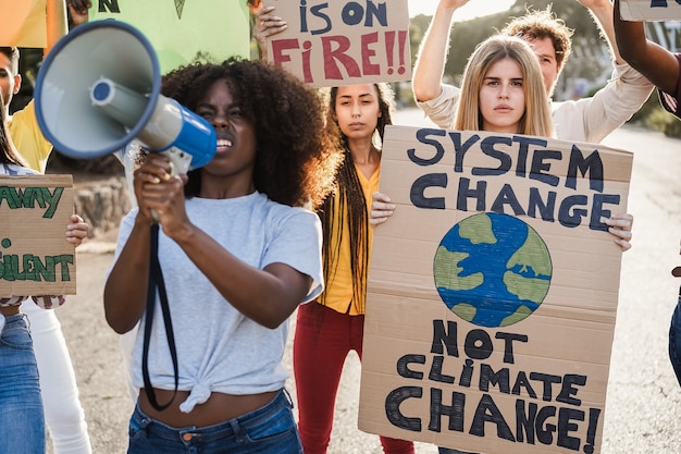 Young group of demonstrators on road from different culture and race fighting for climate change - Focus on right woman face