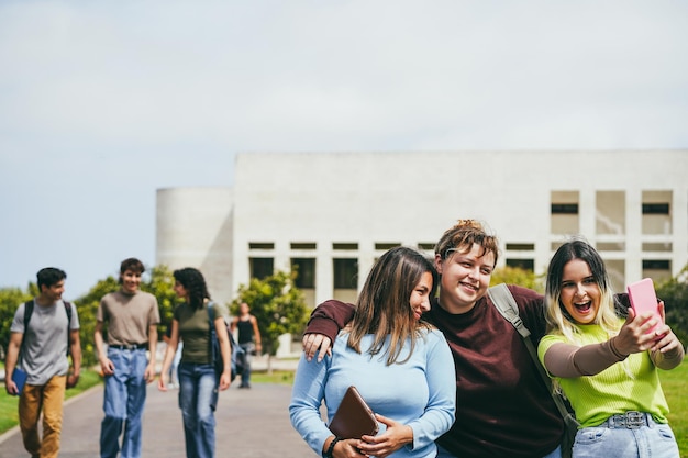 Photo young group of friends having fun doing selfie outside with school building on background focus on girls faces