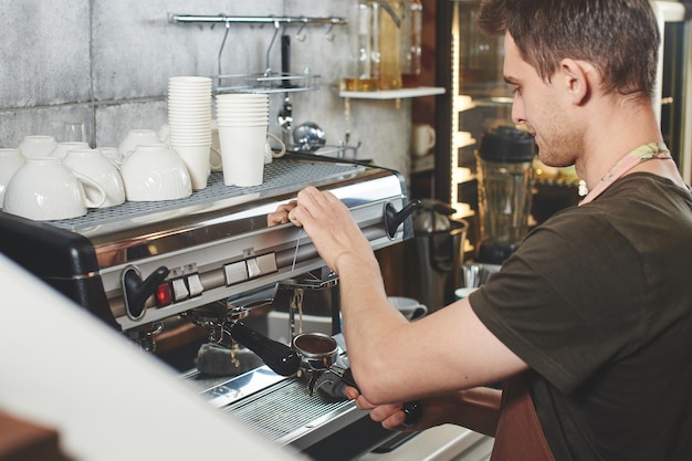 若い男バリスタは喫茶店で働いています。