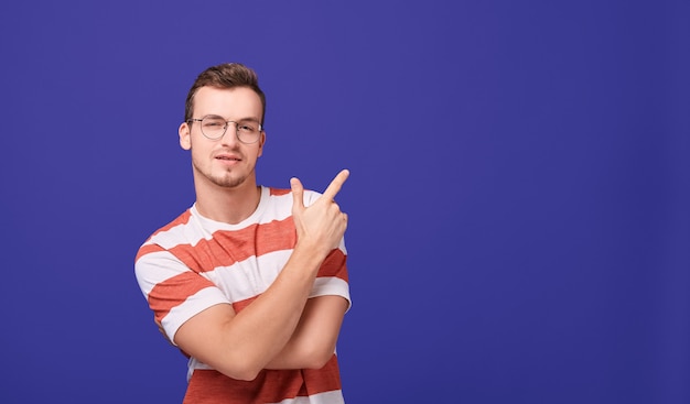 young guy in casual clothes and glasses shows finger to side.