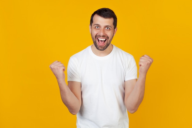 Young guy celebrates success with arms up