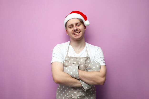 young guy chef in santa hat and apron stands with his arms crossed and smiles