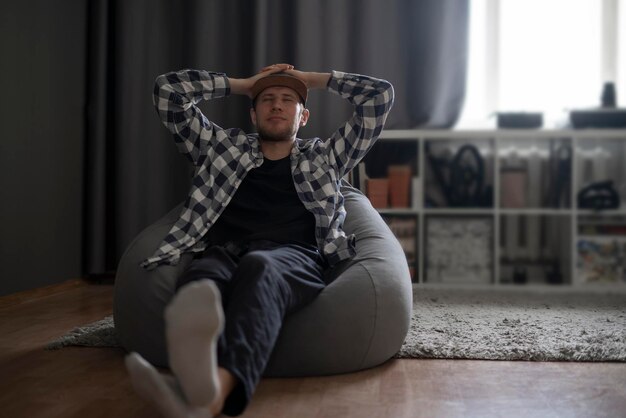 A young guy chill and relax on the soft bag couch pouf at home