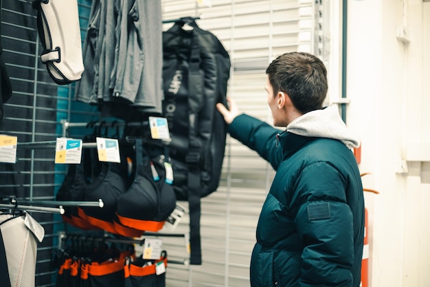 A young guy chooses a backpack in a store