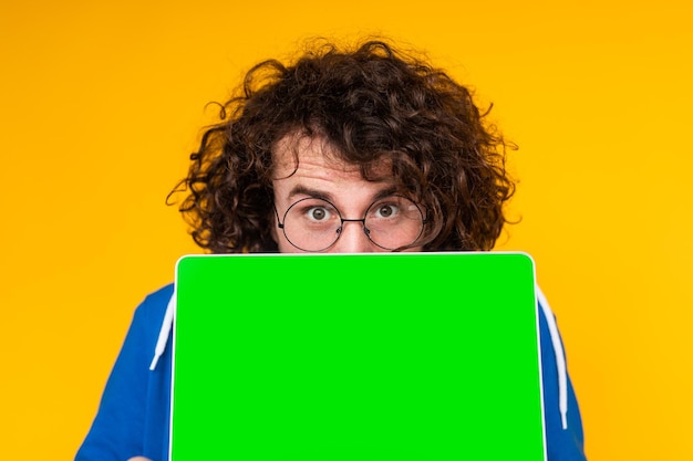 Young guy covering mouth with netbook with green screen