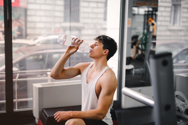 Young guy drinking in the gym