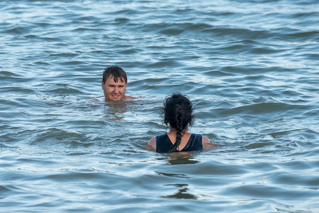 若い男と女が湖で泳ぐ