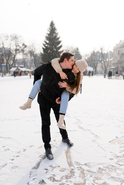 Young guy and girl in winterwear enjoying snowfall