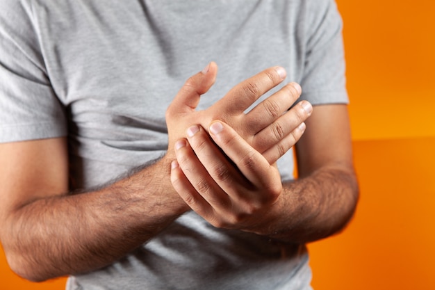 Young guy has a sore arm on a orange background