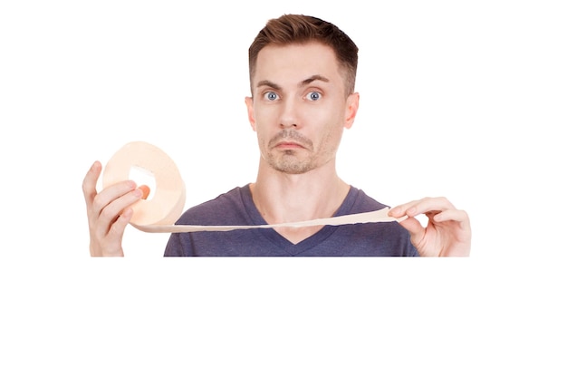 Young guy holding a roll of toilet paper on a white background. Copy space.