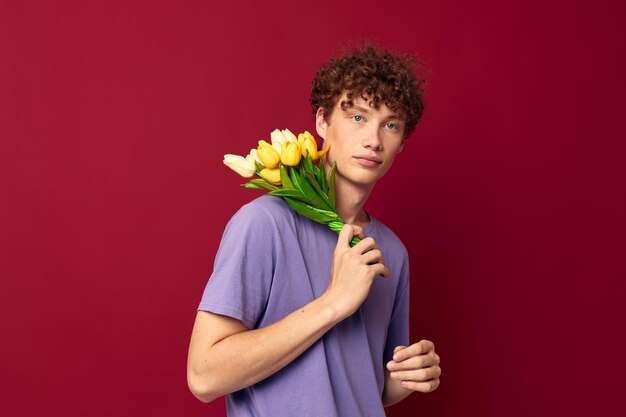 Young guy holding a yellow bouquet of flowers purple tshirts isolated background unaltered