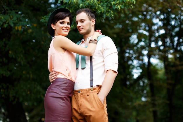 Young guy holds his lover by the waist, the girl is happy with a smile on his face