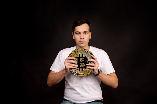 Foto un giovane ragazzo detiene un simbolo della moneta bitcoin, una valuta moderna per lo scambio e gli acquisti