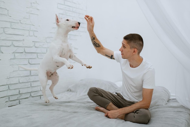 写真 明るい部屋の若い男が犬と遊んでいる