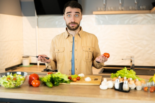 Young guy is curious about cooking vegetarian food. Handsome man doesn't know what to cook