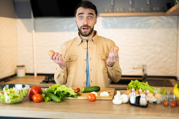 Il giovane è curioso di cucinare insalata vegetariana. un bell'uomo non sa cosa cucinare