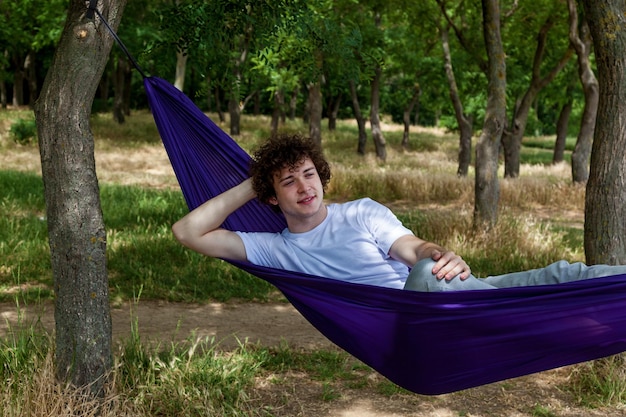 Foto un giovane sta riposando in un'amaca viola in natura godendosi la solitudine e il silenzio