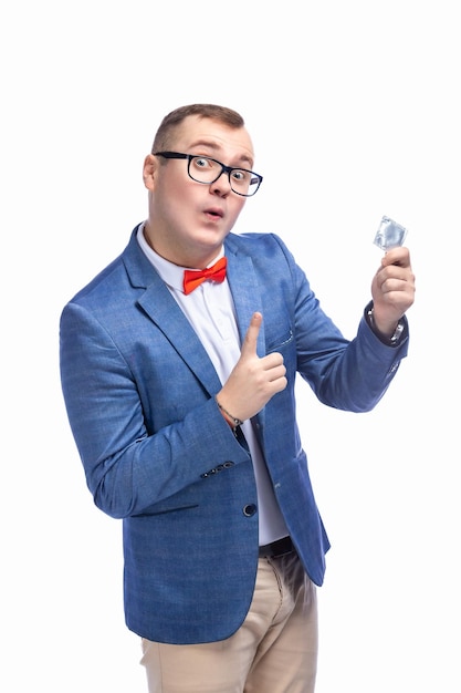 Young guy in a jacket bow tie glasses holds a condom in his hand isolated on white background