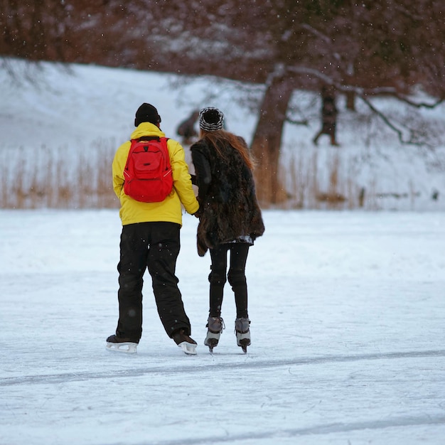 冬のトラカイの凍った湖で女の子アイススケートを学ぶ若い男。スケートには、スケート靴を使って氷上を移動することからなるあらゆる活動が含まれます