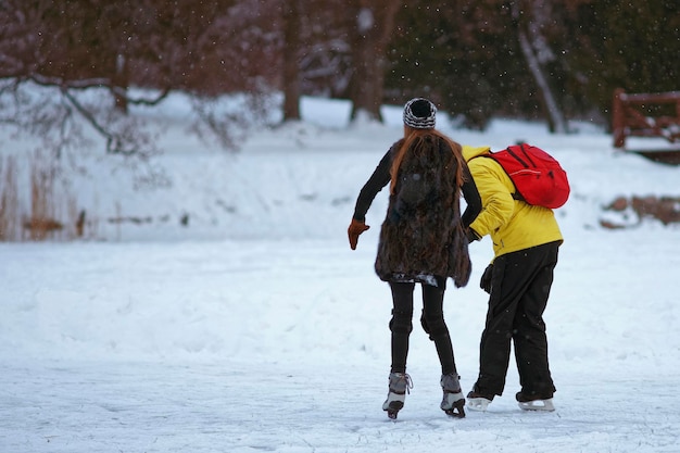 Young guy learning girl Ice skating on ice covered lake in winter Trakai. Skating involves any activity which consists of traveling on ice using skates